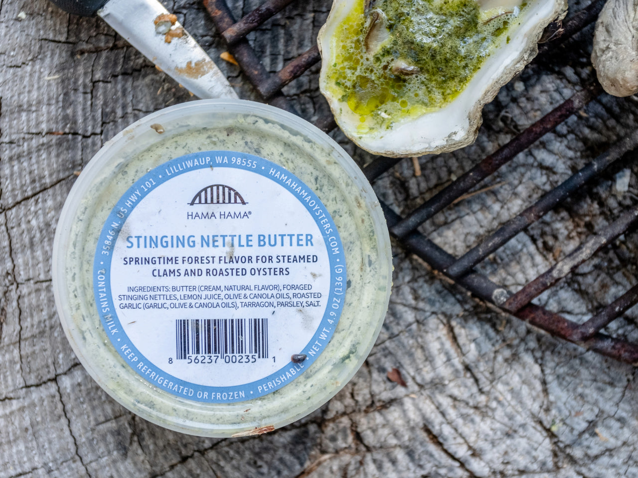 top down view of Hama Hama Oyster Company's house-made stinging nettle butter in a plastic tub next to a grilled oyster with the butter